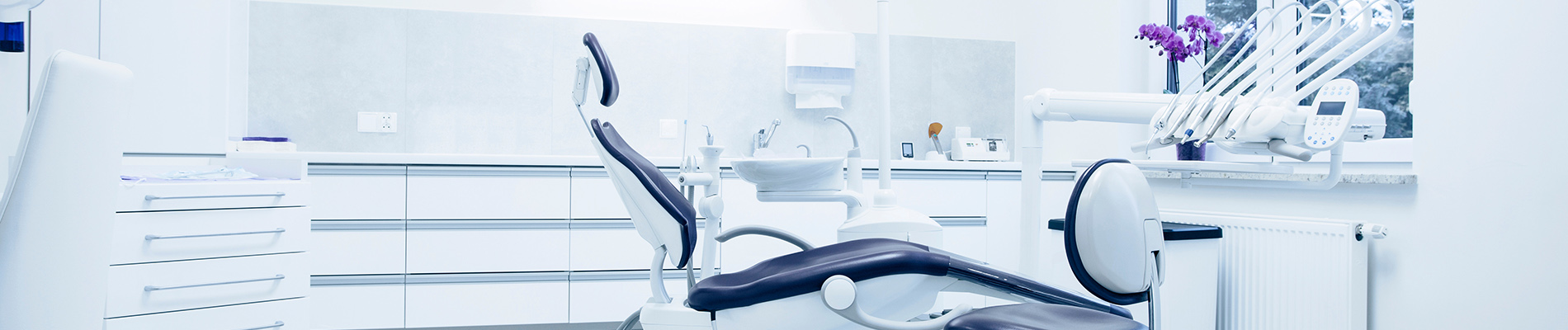 The image shows a modern dental clinic interior with various pieces of equipment, including a dental chair and an X-ray machine.